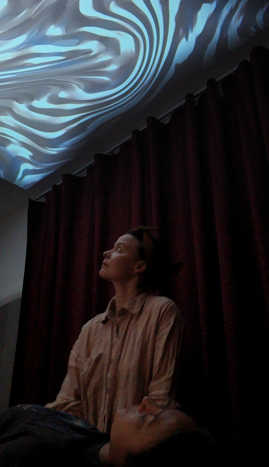 A woman looks up at flowing blue and white visuals projected on the ceiling